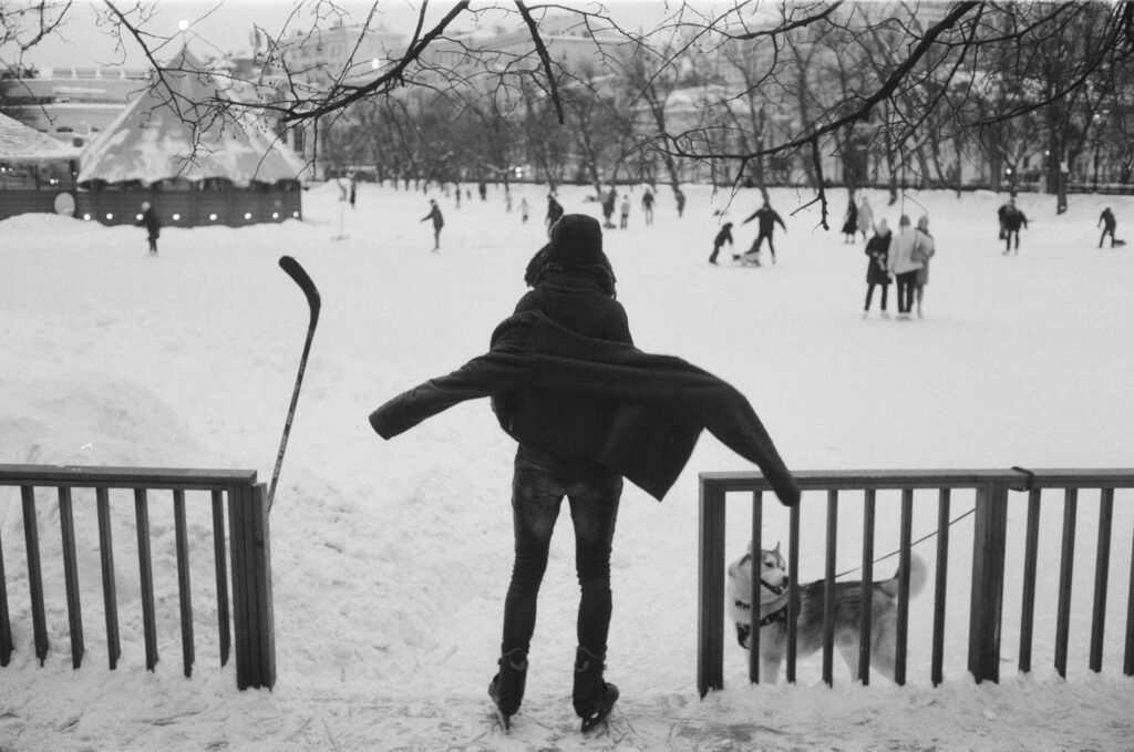 a person standing in the snow with a dog on a leash