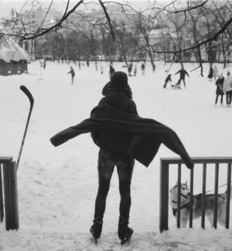 a person standing in the snow with a dog on a leash