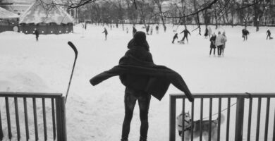 a person standing in the snow with a dog on a leash