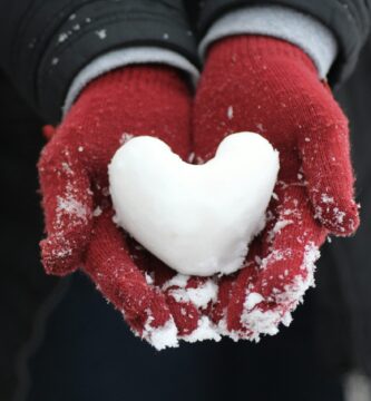 person holding heart-shaped snow