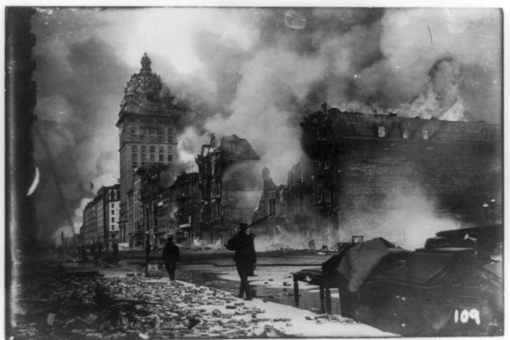 View of street in San Francisco, California, earthquake aftermath with man patrolling with gun.