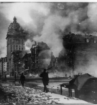 View of street in San Francisco, California, earthquake aftermath with man patrolling with gun.