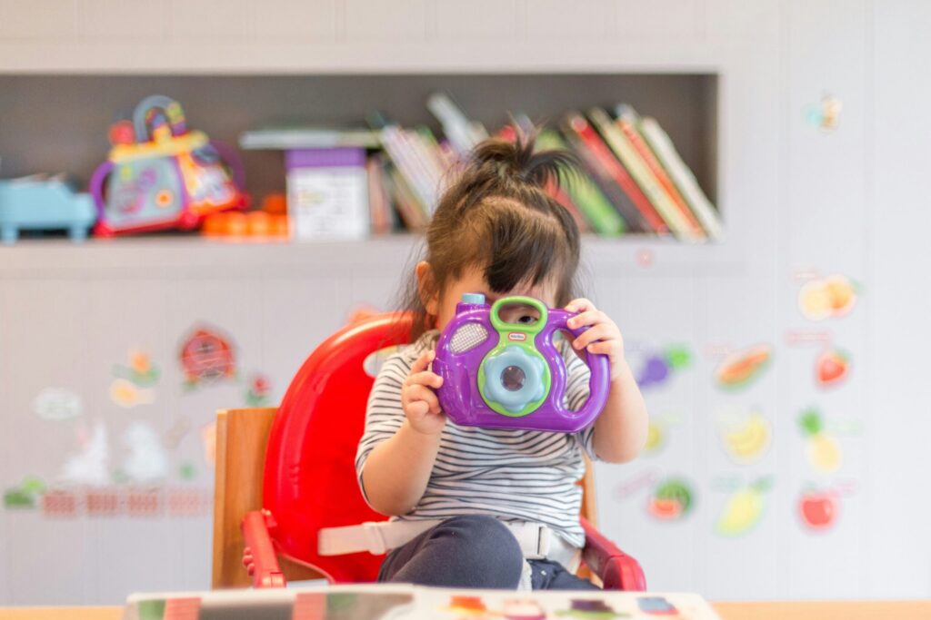 girl holding purple and green camera toy
