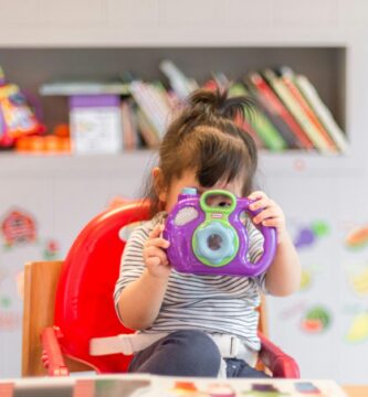 girl holding purple and green camera toy