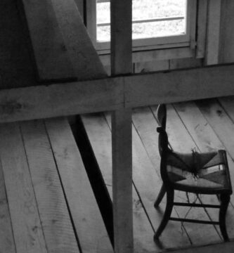 grascale photo of chair near window inside room