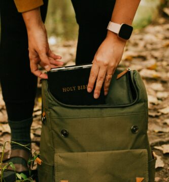 person holding green and black backpack